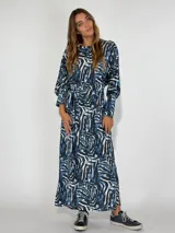 Vestido largo azul con estampado abstracto en blanco y negro, corte recto y mangas largas abullonadas.