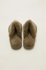 Pantuflas cerradas color marrón con ribetes de piel sintética en la abertura y suela plana.