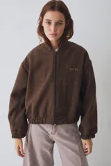 Campera tipo bomber de paño color marrón, con cierre frontal, puños y ruedo elásticos. Presenta un cuello de piel sintética desmontable en color crema y el logo de la marca bordado en el pecho.