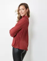 Blusa color ladrillo de gasa plisada con cuello alto, manga larga abullonada con puño y botón de ajuste. Espalda con abertura ojal y doble abotonadura.