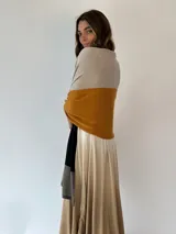 Pashmina de tejido de punto fino con diseño de bloques de color en tonos beige, mostaza, negro y marrón claro.