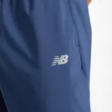 Pantalón deportivo New Balance de corte ajustado, color azul marino, con cintura elástica con cordón de ajuste y puños elásticos en los tobillos. Presenta el logo de la marca estampado en la pierna izquierda.