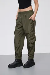 Babucha estilo cargo color verde oliva, confeccionada en tela técnica con acabado satinado. Presenta cintura elástica, bolsillos laterales con solapa y puños elásticos en los tobillos.