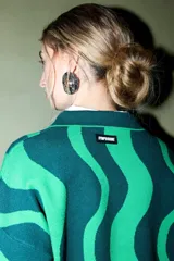 Sweater de tejido de punto con cuello polo y tapeta de botones, presentando un diseño de rayas onduladas anchas en dos tonos de verde.