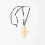 Collar con dije de espina de pescado en metal dorado con textura martillada, suspendido de un cordón negro ajustable.