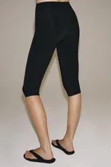 Pantalón capri negro de tiro medio y cintura elástica, confeccionado en hilatura con poliamida.