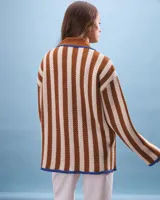 Cárdigan tejido a rayas verticales color marrón y beige, con cuello marrón, cierre con nudos azules y bolsillos frontales ribeteados en azul.