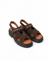 Sandalias de gamuza marrón con tiras cruzadas en el empeine y una tira superior decorada con tachas metálicas doradas. Poseen suela chunky negra con plataforma y plantilla de cuero tostado.