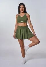 Conjunto deportivo compuesto por un top de escote en V con logo estampado y una pollera tableada de tiro alto, ambos en color verde militar.