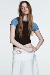 Falda midi blanca de tiro alto con efecto fruncido o drapeado en la cintura y caída acampanada.