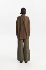 Camisa de manga larga color marrón, con cuello camisero y botones frontales. La prenda se anuda en la parte inferior central, dejando ver parte del abdomen.