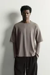Camiseta de corte relajado confeccionada en algodón con elasticidad, con cuello redondo y diseño de manga larga con efecto doble. Presenta un acabado con efecto lavado.