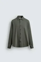 Camisa de corte regular fit color celeste, confeccionada en tejido fácil de planchar. Cuenta con cuello italiano abierto, manga larga con puño abotonado y cierre frontal con botonadura.
