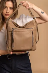 Cartera mochila versátil de cuero sintético con textura granulada, color negro. Cuenta con múltiples bolsillos frontales con cierre, correas ajustables que permiten su uso tanto como cartera de hombro o como mochila, y herrajes metálicos.