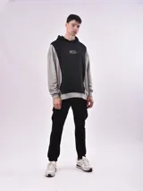 Canguro gris con capucha y mangas largas. Presenta un panel frontal negro con bolsillo tipo canguro y estampado con la frase "Dream Without Limits".