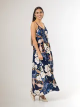 Vestido largo de satén azul marino con tirantes finos y escote en V, con gran estampado floral en tonos blancos, celestes y marrones, y diseño de caída fluida.