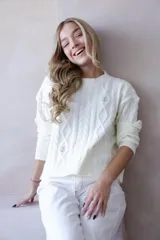 Sweater color crema de punto con diseño de ochos y flores bordadas. Cuello redondo y mangas largas.