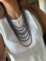Collar de cuentas de vidrio en múltiples hilos de color turquesa, borgoña y morado.