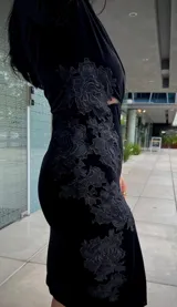 Vestido midi de terciopelo negro, con mangas largas, cuello redondo y detalle de encaje bordado en el lateral de la cintura.