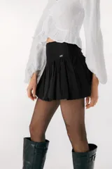 Falda corta tipo balloon color blanco, con cintura alta y diseño con volumen. Presenta una pequeña placa metálica con el logo de la marca en la parte frontal.