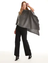 Poncho tejido de punto con diseño asimétrico y aberturas laterales para los brazos.