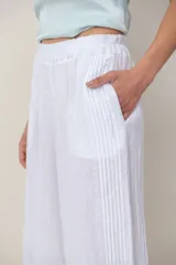 Pantalón palazzo de lino color blanco, con cintura elástica fruncida, bolsillos laterales y detalle de alforzas verticales en los laterales.
