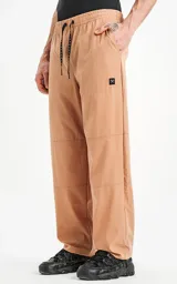 Pantalón de corte recto confeccionado en microfibra liviana y ligeramente elastizada. Presenta cintura elástica con cordón de ajuste, bolsillos laterales y un bolsillo trasero con tapa y velcro. Incluye recortes horizontales en las piernas y un pequeño logo bordado en el muslo.