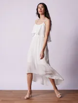 Vestido midi blanco de gasa bambula marca Lily Black, con escote redondo, breteles regulables y lazo de ajuste. Presenta una sobrecapa en el torso y un forro interno a tono. El largo de la espalda es mayor al largo delantero.