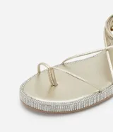 Sandalias planas doradas con tiras finas, lazo para atar al tobillo y suela forrada en cristales.