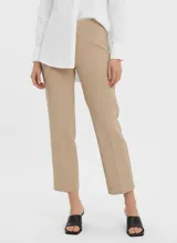 Pantalón de vestir color beige claro, tiro alto, corte recto y largo al tobillo. Presenta pinzas frontales y un acabado liso y elástico.