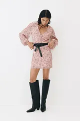 Vestido corto de gasa arrugada en color rosado con estampado floreado, escote en V y costura fruncida central con botones decorativos forrados. Cuenta con mangas globo largas con puños elásticos y cierre oculto en la espalda.