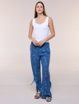 Pantalón palazzo de rayón color azul con estampado paisley blanco, corte amplio, tiro medio-alto con pretina elastizada y aberturas laterales en el puño regulables con lazos.