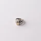 Anillo de diseño robusto fabricado en plata 925 con detalles centrales en oro, presentando una estructura con líneas diagonales grabadas.