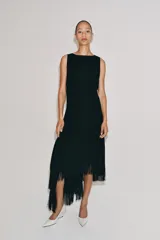 Vestido midi de Zara Woman Collection color negro, sin mangas, con cuello redondo y espalda abierta. Presenta un diseño asimétrico en el bajo adornado con flecos a tono, y cierre trasero con cremallera y botón.