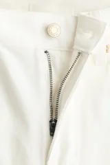 Jean de tiro alto y pierna ancha en denim de algodón blanco, con diseño de cinco bolsillos y bajo sin rematar. Incluye un cinturón de gamuza marrón con hebilla metálica.