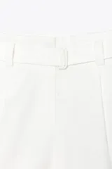 Bermuda blanca de tiro alto con cinturón con hebilla forrada, pinzas delanteras, bolsillos frontales y falsos bolsillos de vivo en espalda. Cierre frontal con cremallera, botón interior y ganchos.