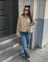 Chaqueta tipo bomber de calce holgado, confeccionada en gamuza color beige. Presenta cuello camisero, cierre frontal, mangas amplias y largo a la cintura.