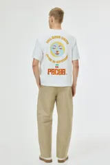 Remera de algodón color blanco con cuello redondo y mangas cortas. Presenta un estampado frontal con el logo de Pacha Ibiza en tonos naranja y amarillo.