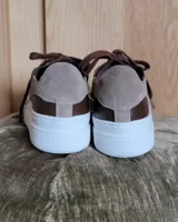 Zapatillas plateadas de cuero con cordones grises y suela blanca.