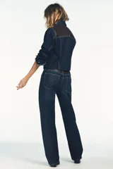 Jeans de tiro alto y pierna ancha con diseño de cinco bolsillos. Presenta una aplicación en la cintura de piel a contraste y cierre frontal con cremallera y botón metálico.