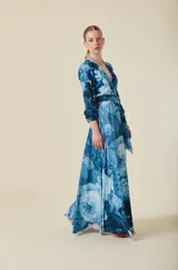Vestido largo de crepé liviano con estampado floral en tonos azules. Presenta escote en V, mangas largas y falda amplia con movimiento. Incluye un lazo en la cintura que permite un ajuste entallado.