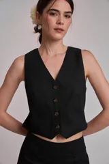 Chaleco corto de corte sastrero en color marrón, con escote en V y cierre frontal con botones a tono.