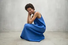 Vestido negro de corte holgado, largo midi o maxi, sin mangas y con cuello redondo.