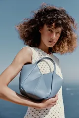 Bolso mini shopper de cuero sintético en color marrón, con diseño estructurado y costuras decorativas contrastantes. Cuenta con doble asa de mano y cierre magnético.