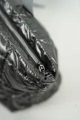 Cartera tipo shopper de color negro, con diseño acolchado y costuras cuadradas. Cuenta con doble asa larga para llevar al hombro y cierre superior.