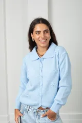 Saco tejido de punto color celeste, con cuello tipo polo, cierre frontal con botones a tono y diseño con flores bordadas en relieve. Posee mangas largas con puños acanalados y ruedo elástico.