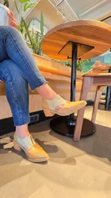 Zapatos de cuero color tostado con puntera fina y tacón bajo, estilo botineta destalonada con laterales abiertos y paneles elásticos en el empeine.