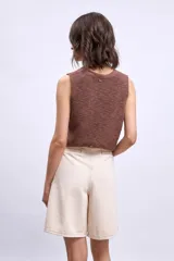 Chaleco de punto color marrón, con escote en V y cierre frontal con botones dorados.