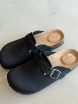 Zuecos negros con hebilla plateada ajustable y plantilla anatómica de corcho.