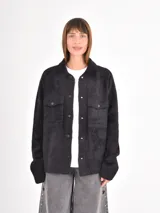 Campera de textura afelpada en color negro, con cierre frontal de botones a presión, cuello camisero y bolsillos frontales con solapa.